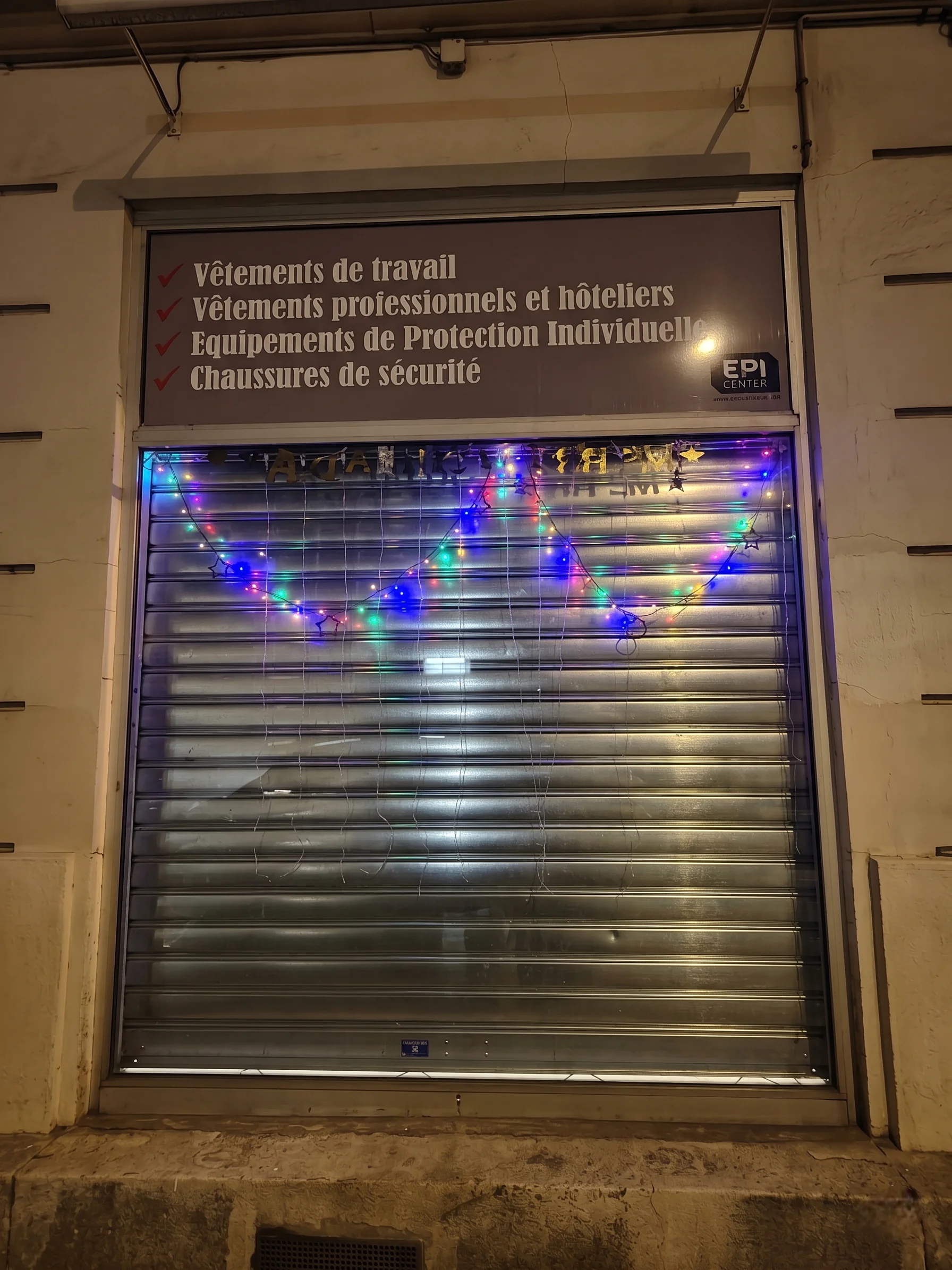 Installation de rideau métallique motorisé à lames pleines pour la boutique de vêtements de travail et d'équipements de protection individuelle à Montreuil.