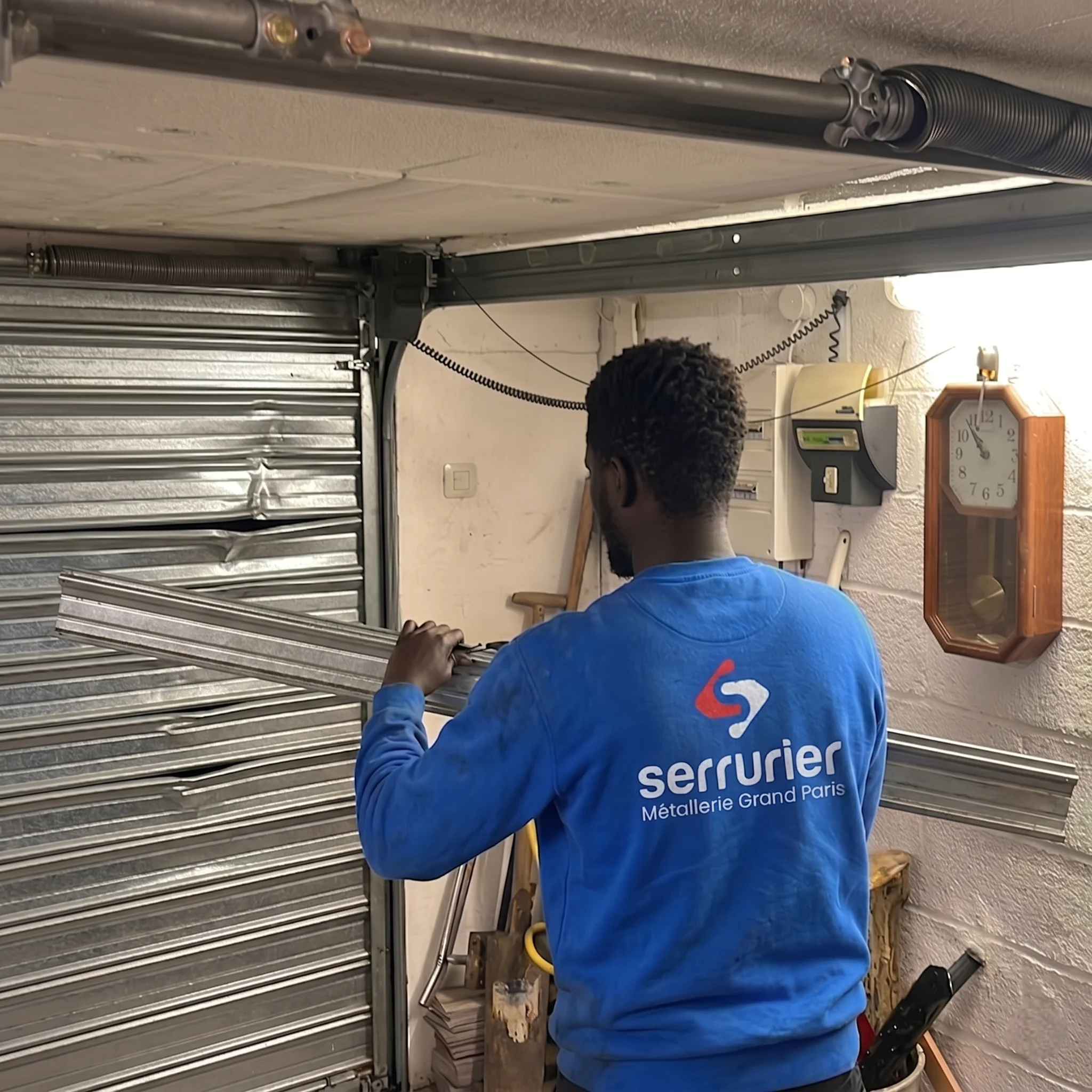 Technicien MGParis remplaçant des lames de rideau métallique endommagées dans un garage à Montreuil.