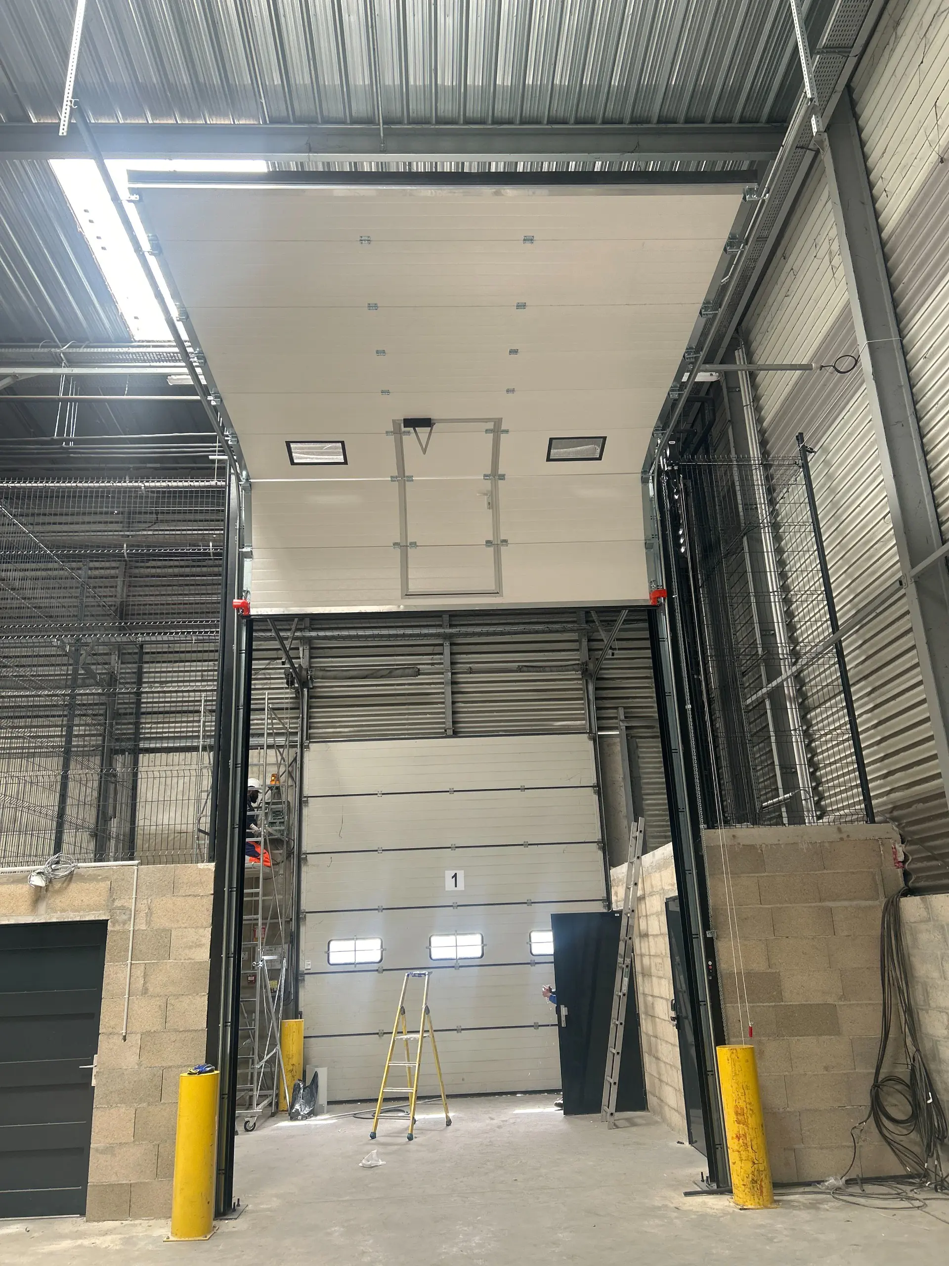 Porte sectionnelle industrielle motorisée avec portillon et hublots installée à Bonneuil-sur-Marne par MGParis 2