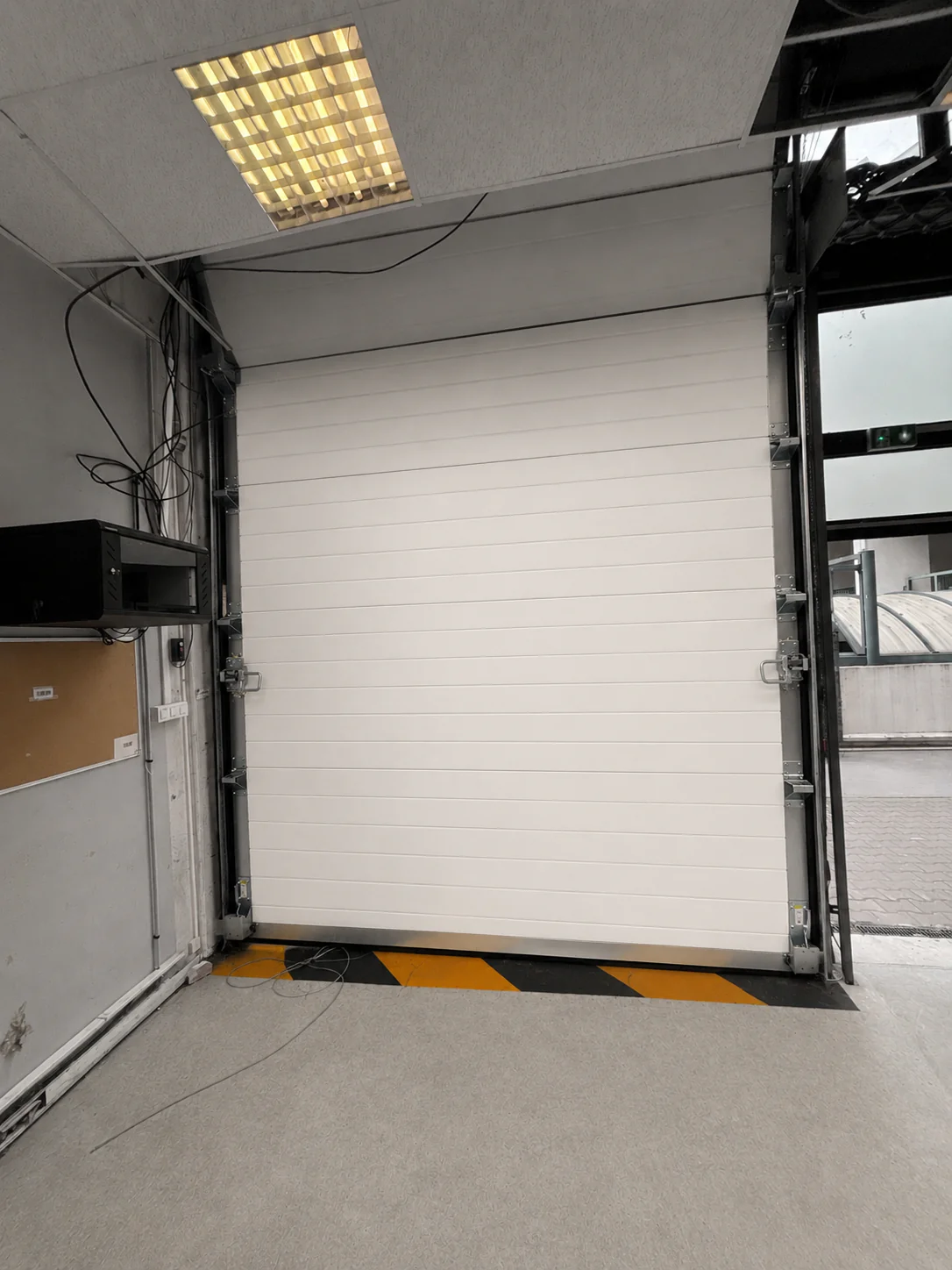 Porte sectionnelle industrielle bloquée à Bagnolet 93170 en raison de câbles de levage usés et hors service nécessitant un remplacement urgent.
