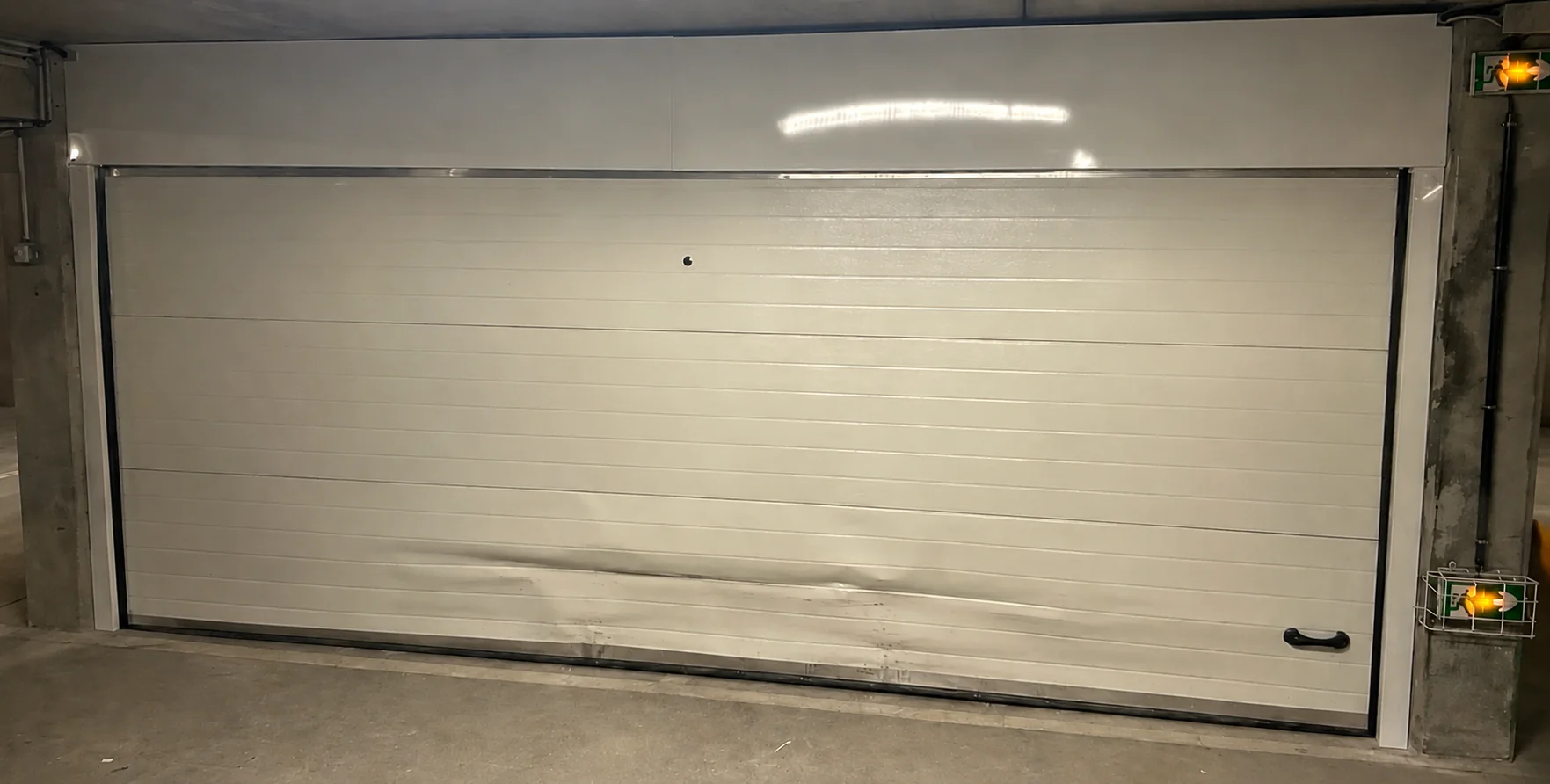 Panneau inférieur déformé après un choc sur une porte de garage sectionnelle à Chaville (92370)