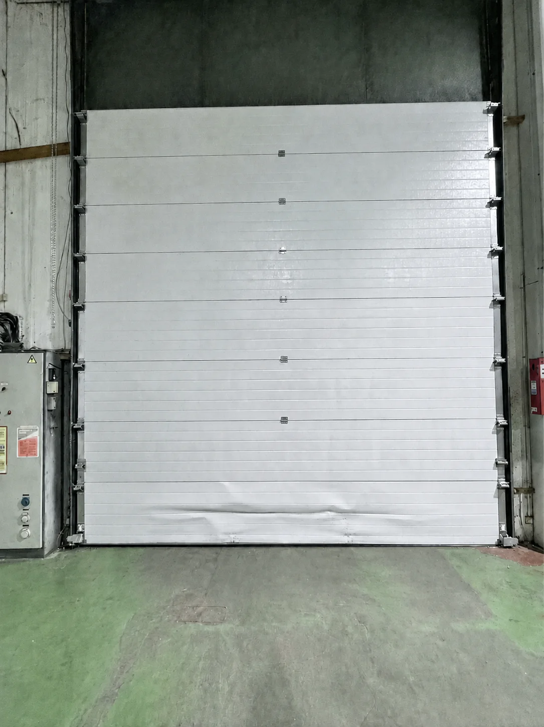Porte sectionnelle industrielle endommagée à Valenton avec panneau inférieur fortement déformé suite à un impact provoquant le blocage de la porte