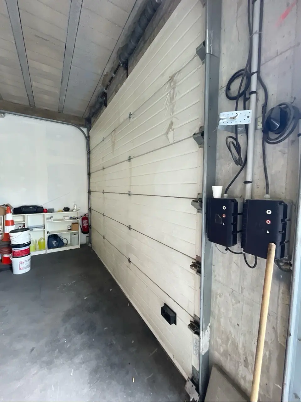 Porte sectionnelle industrielle bloquée fermée avant remplacement des câbles de levage à Crosne (91560)