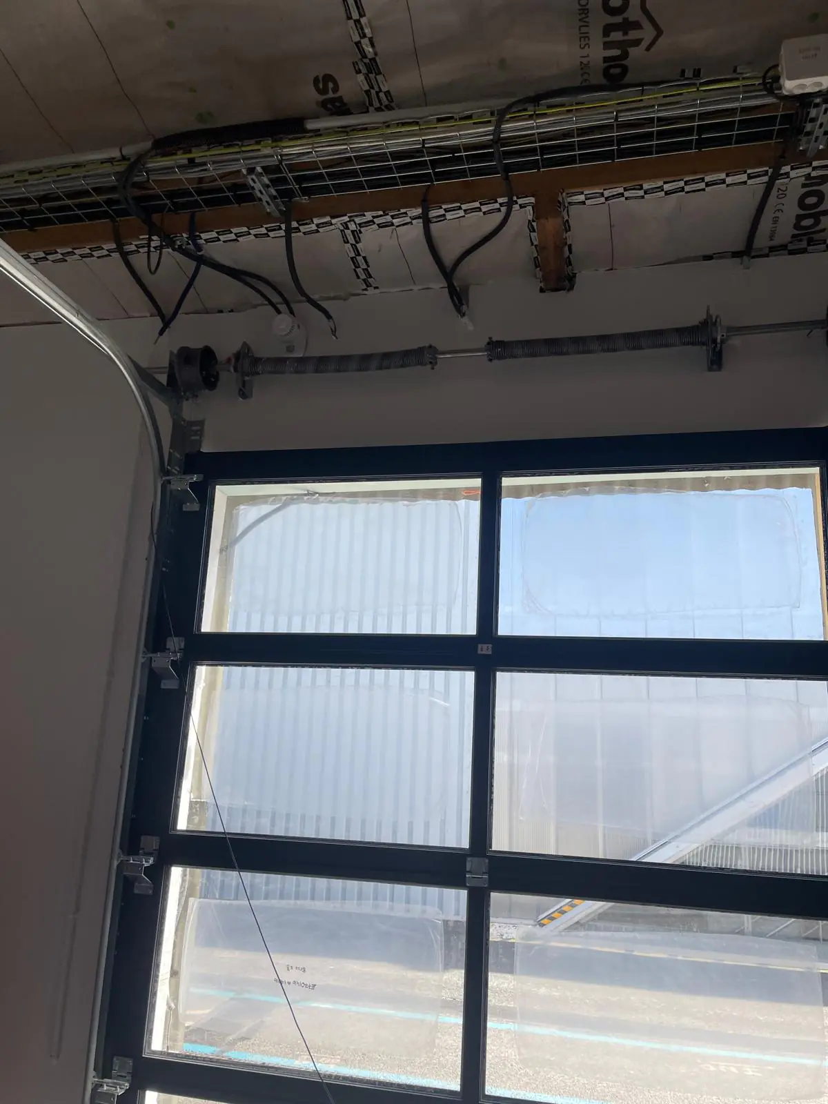 Porte sectionnelle industrielle vitrée bloquée avant remplacement des ressorts de torsion à Vaires-sur-Marne (77360)