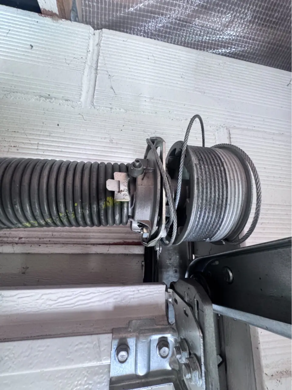 Porte de garage sectionnelle remise en service après le remplacement des ressorts de torsion et de la paire de câbles de levage à Brétigny-sur-Orge (91220).
