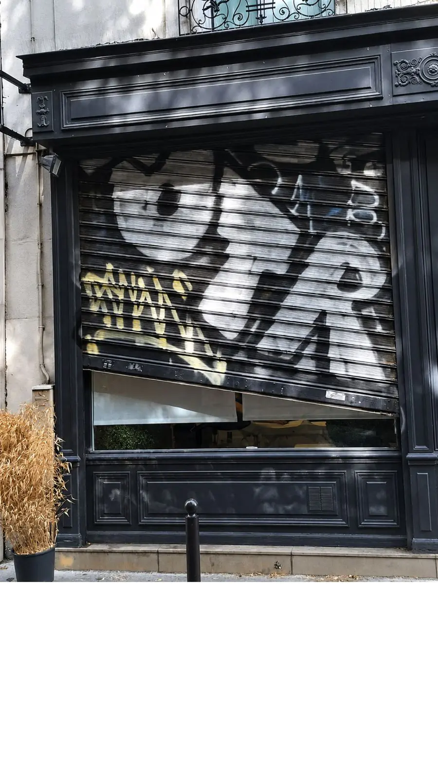 Rideau métallique à lames pleines bloqué à mi-hauteur avec lames sorties des coulisses et inclinées à Paris 11