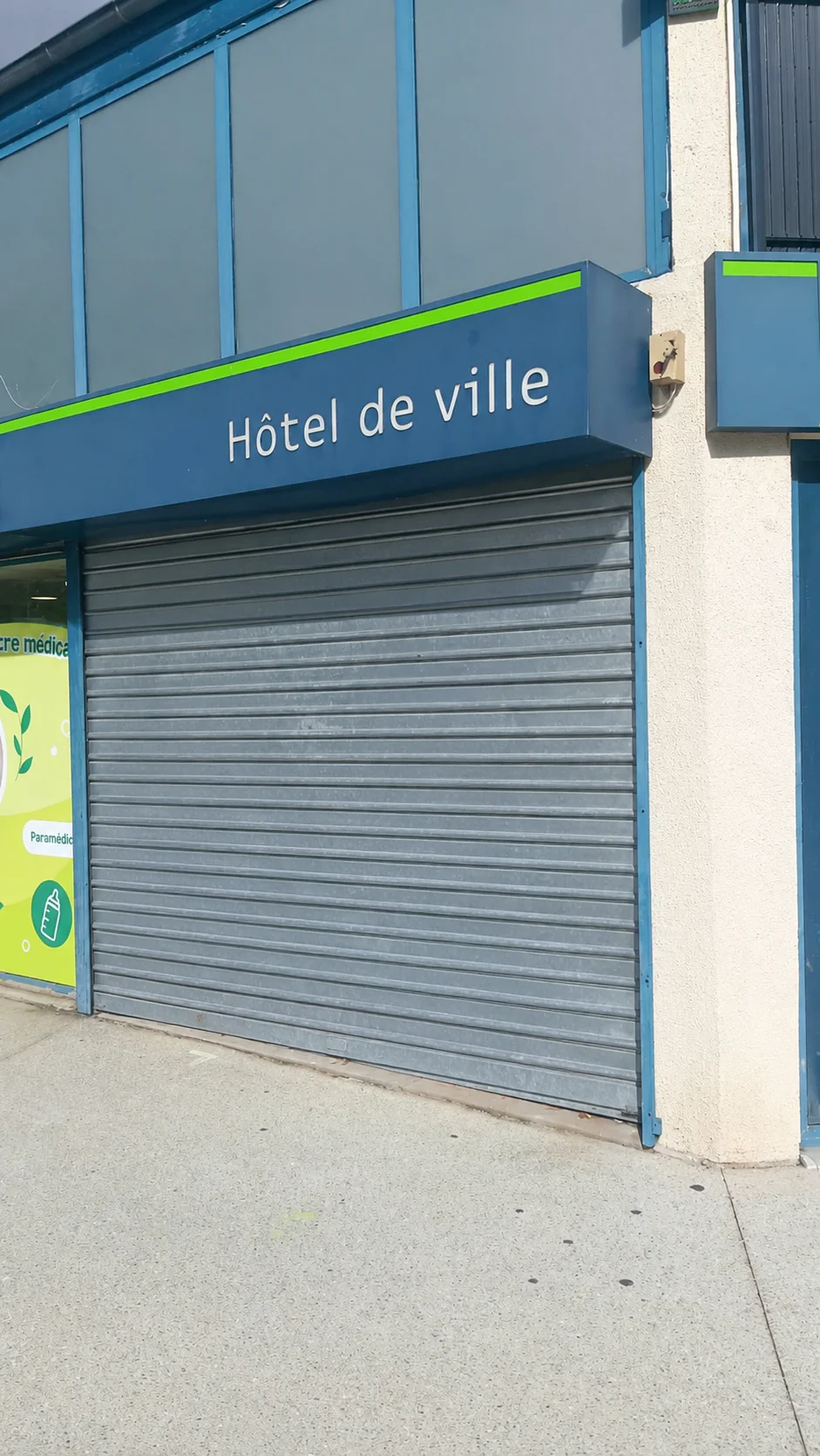 Rideau métallique à lames pleines bloqué fermé avant réparation à la Pharmacie Hôtel de Ville à Fontenay-le-Fleury