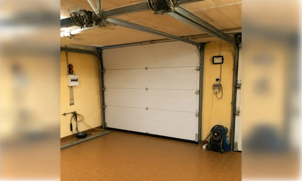 Porte de garage sectionnelle blanche vue de l’intérieur du garage, avec ses rails, à Châtenoy