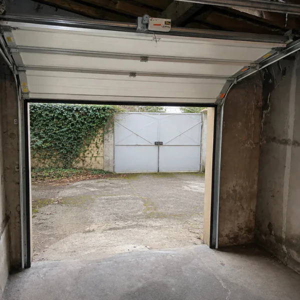 Vue intérieure d'une porte de garage sectionnelle ouverte avec son moteur : réparation à Gometz-la-Ville