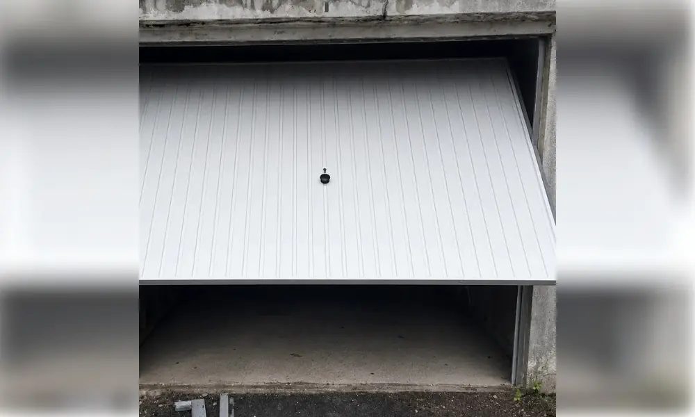 Porte de garage basculante blanche à rainures verticales, entrouverte, dépannage à Châtenoy