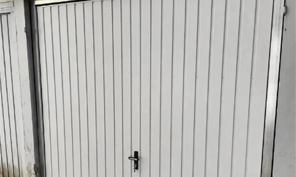 Porte de garage basculante blanche d’une remise, réparée à Arville