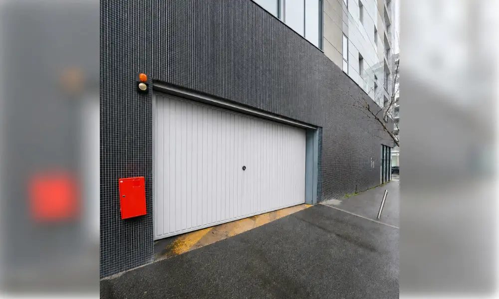 Porte de garage blanche à lames verticales à l’entrée d’un parking d’immeuble à Chailly-en-Brie (77120)