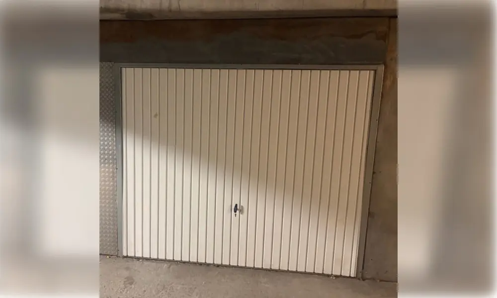 Porte de garage basculante blanche à rainures verticales dans un box en béton, Châteaubleau