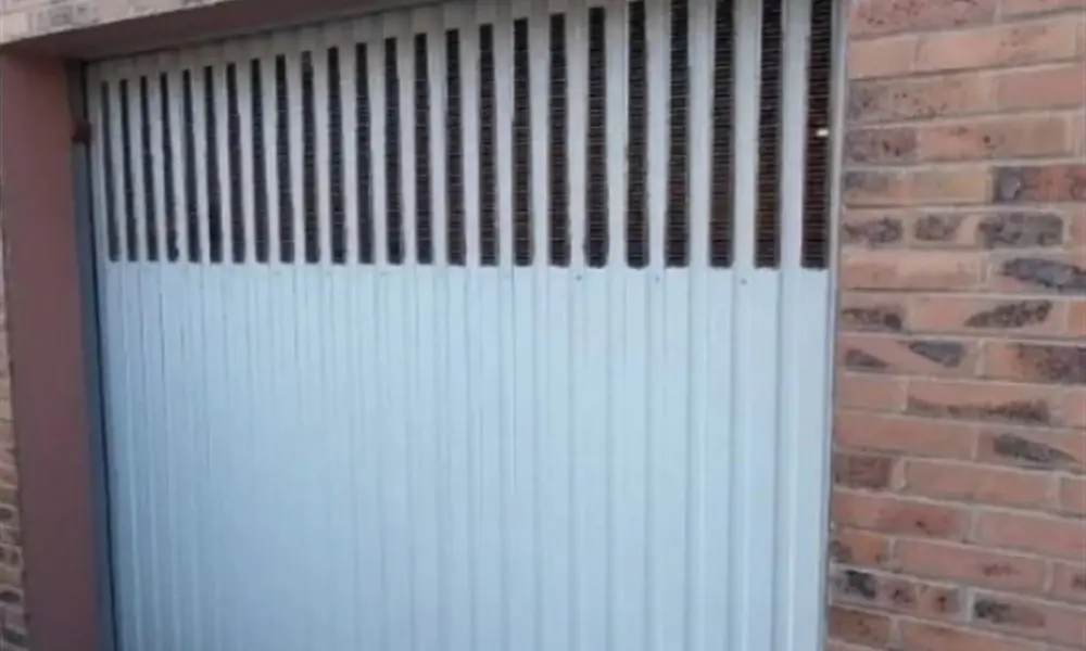 Exemple de porte coulissante à lames ajourées prise en charge pour une réparation de porte de garage à Saint-Hilaire