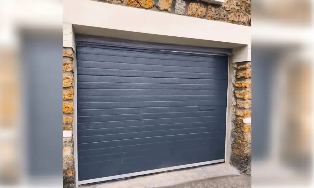 Porte de garage sectionnelle anthracite encadrée de pierres ocre à Chailly-en-Brie (77120)