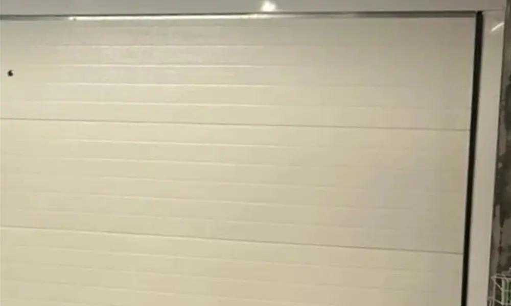 Porte de garage sectionnelle crème d’un pavillon de Vauhallan (91430) remise en état par MGParis