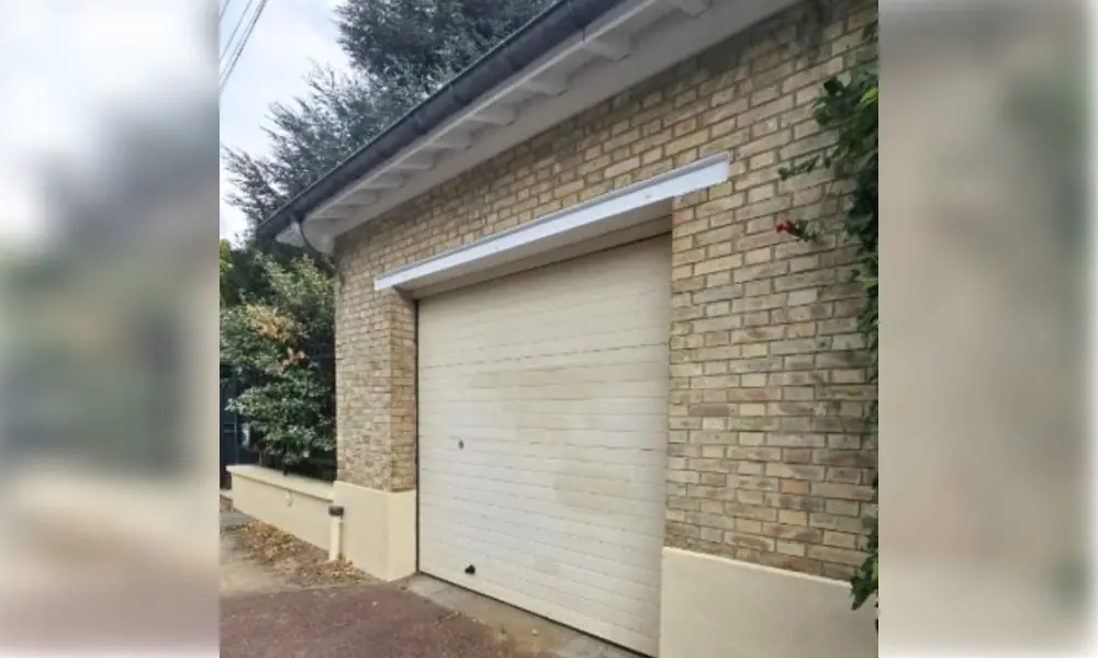 Porte de garage sectionnelle crème dans une façade en briques jaunes, Carnetin (77400)
