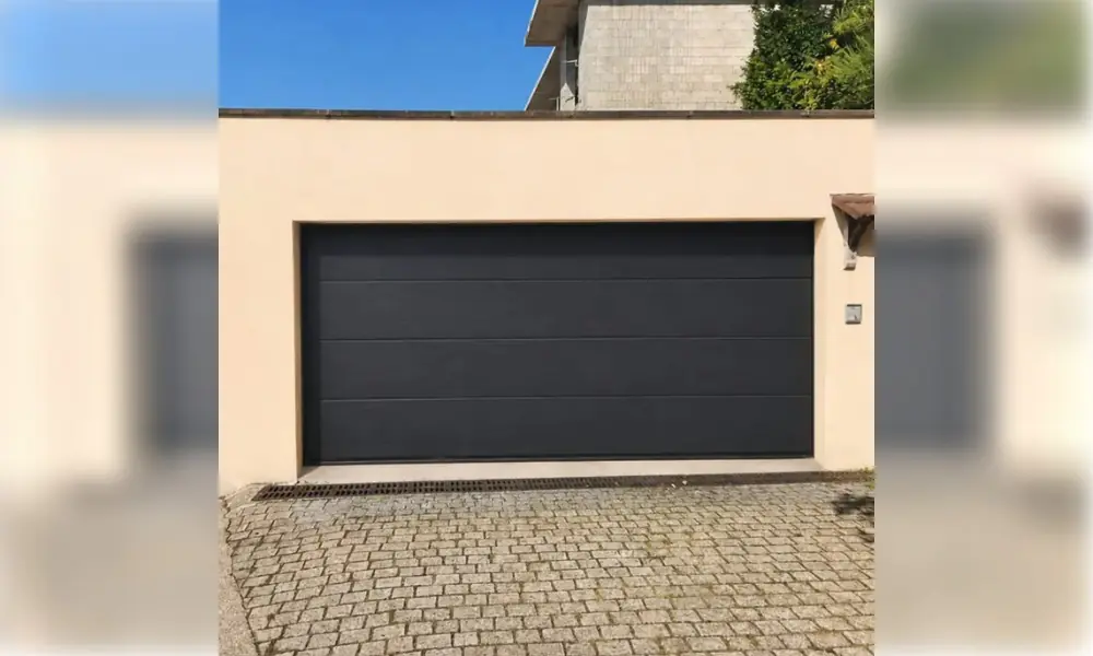Porte de garage sectionnelle anthracite sur une façade beige à Dhuisy