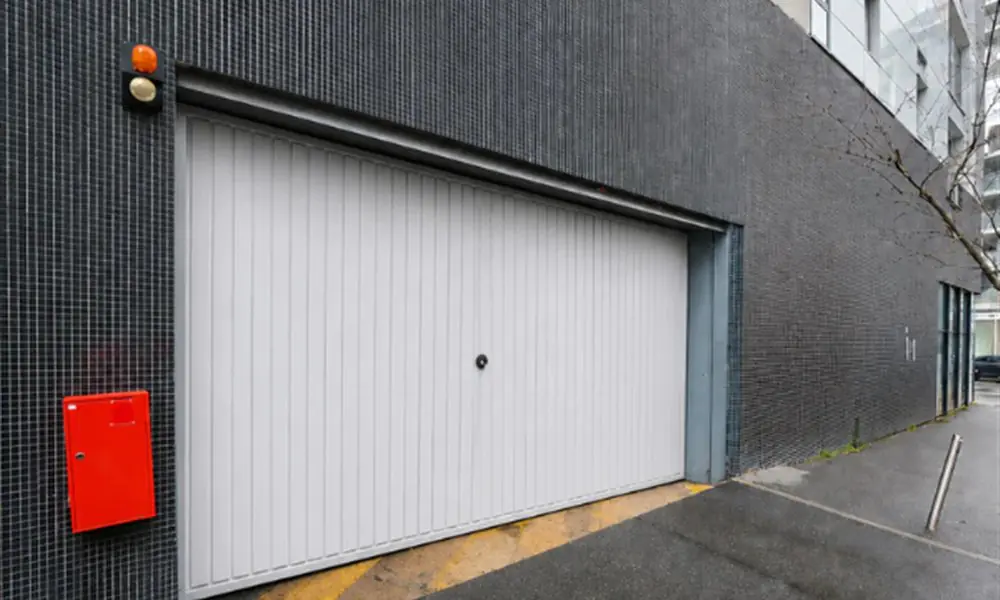 Réparation porte de garage Villejust 91140 : porte sectionnelle blanche d’une résidence